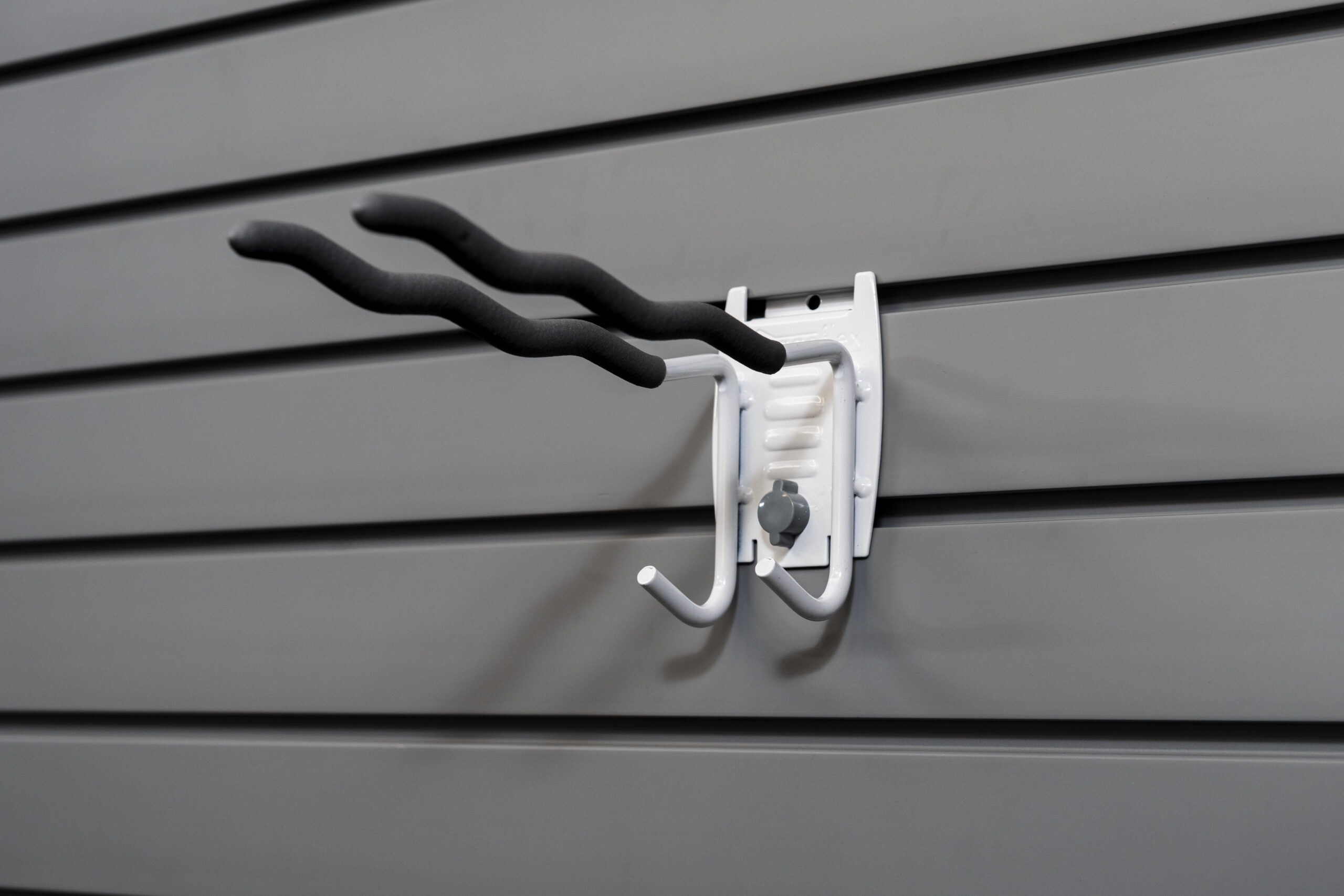 Multi-purpose tool hook on slatwall holding various items